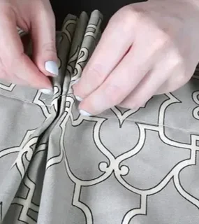 A close-up of hands adjusting pleats on elegant patterned fabric
