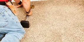 A construction worker kneels on a textured surface