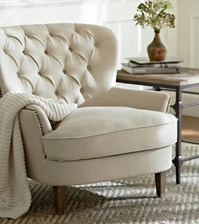 Cozy beige tufted armchair with a soft blanket draped over it