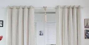 Light, textured beige curtains hang from a white rod