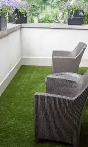 Two modern wicker chairs on a green artificial grass patio