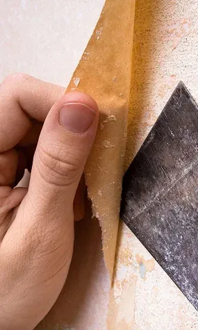 hand peeling back a layer of old wallpaper