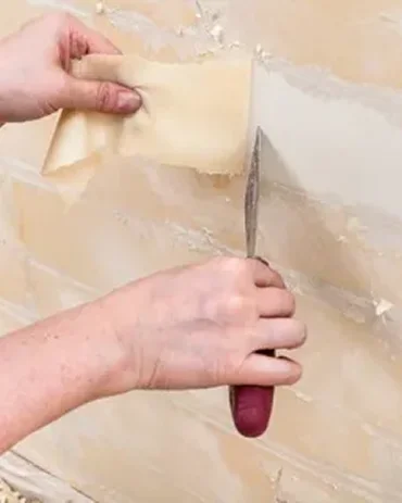person scrapes a wallpaper