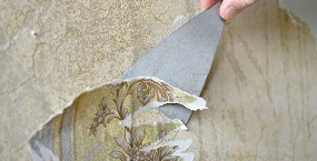 person’s hand peels back layers of wallpaper